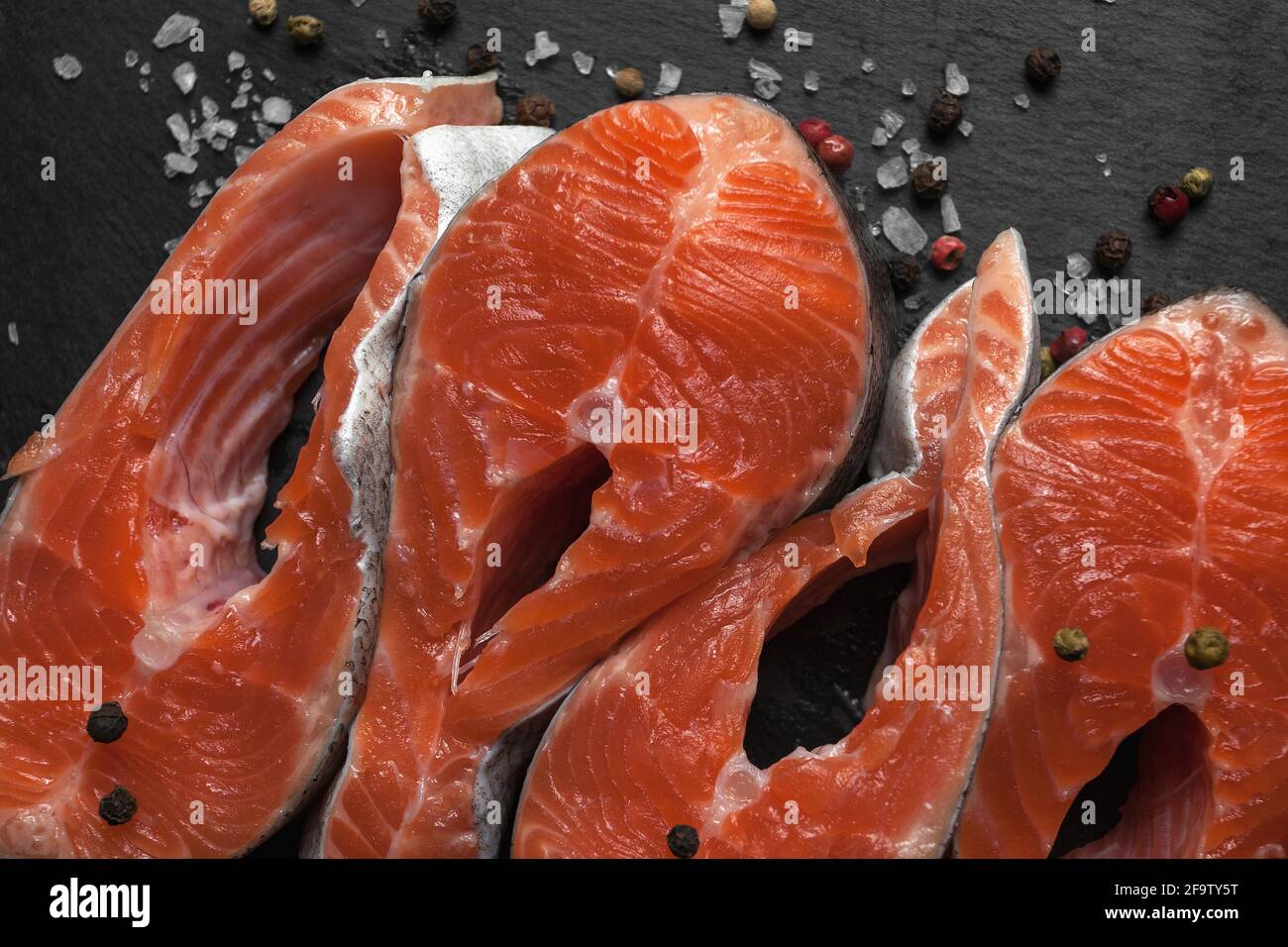 Fresh raw salmon steak with spices, prepared for grilling or roasting. Healthy seafood food.  Stock Photo