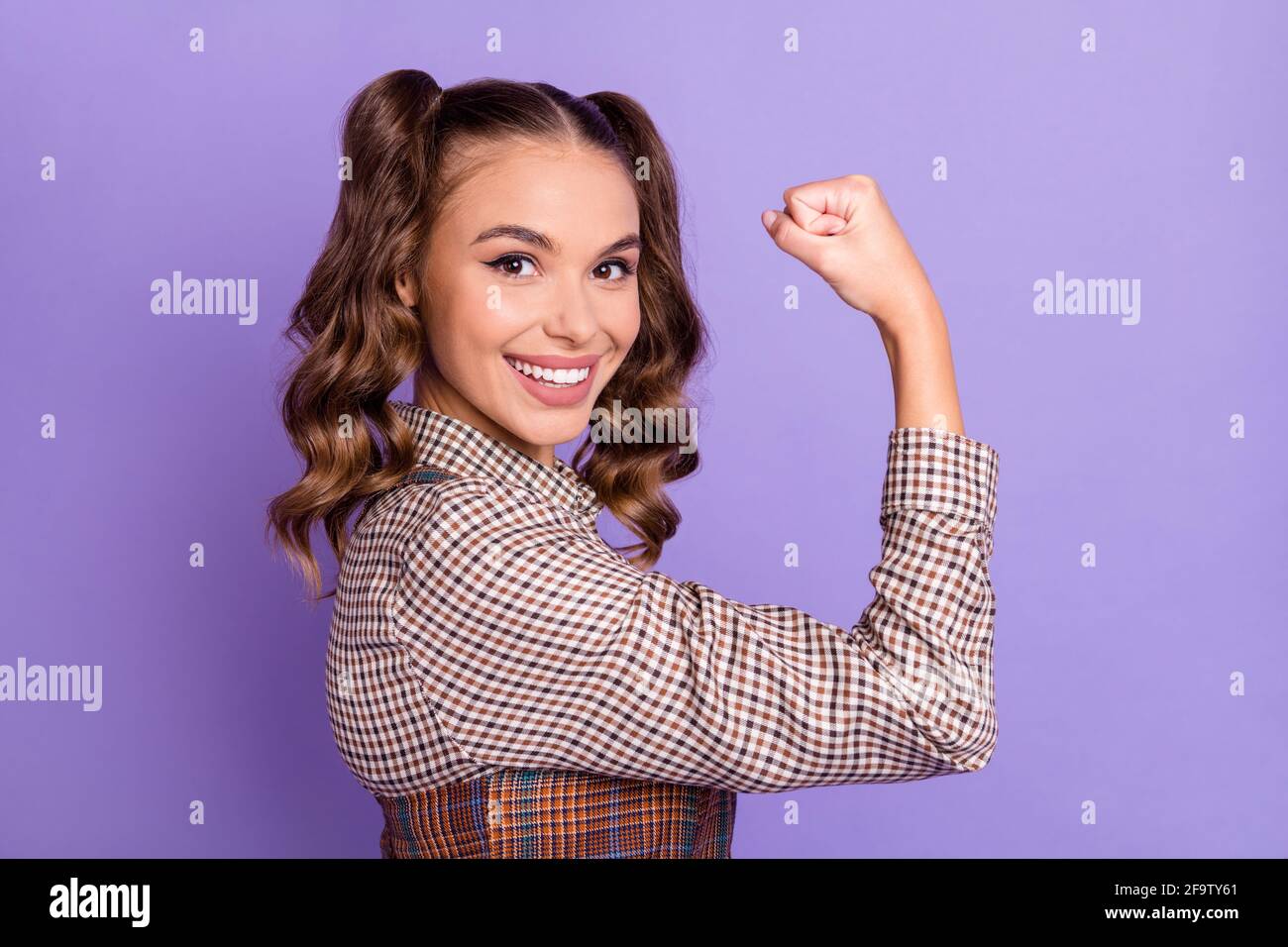 Profile portrait of adorable person arm flexing biceps look camera isolated on purple color background Stock Photo