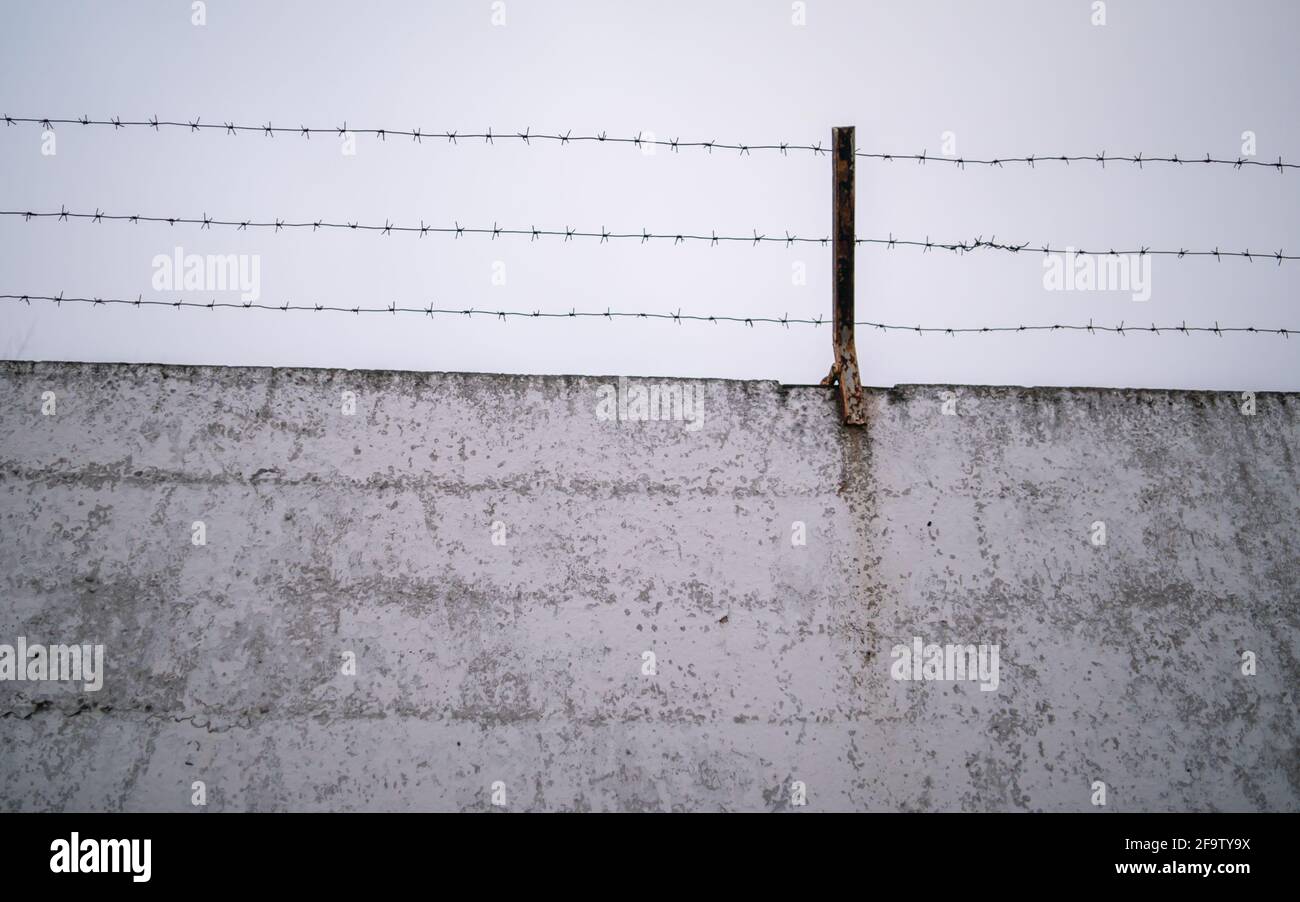 Rusty barb wire on the top of a old concrete fence Stock Photo - Alamy