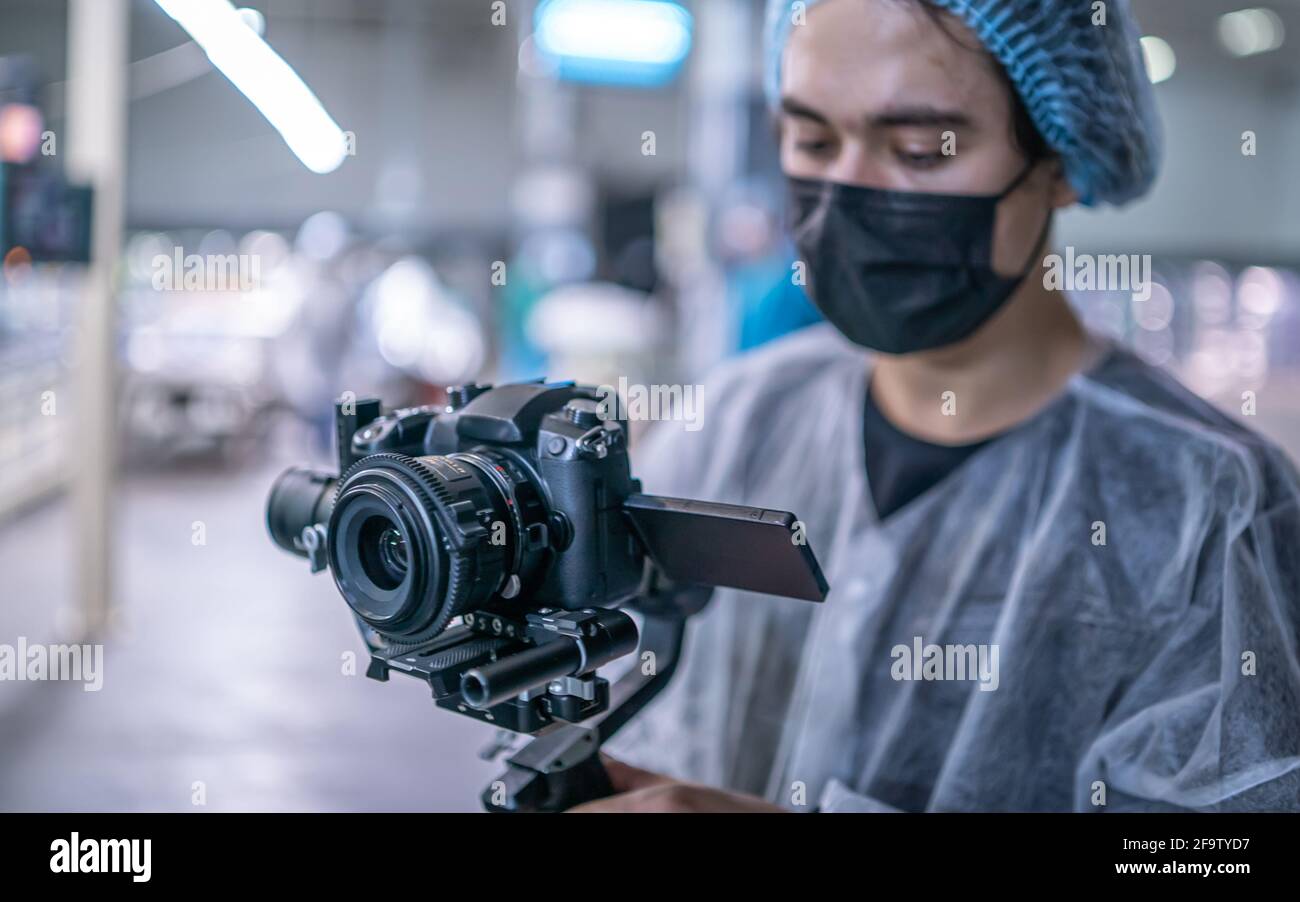 Young operator in medical protective suit with camera Stock Photo