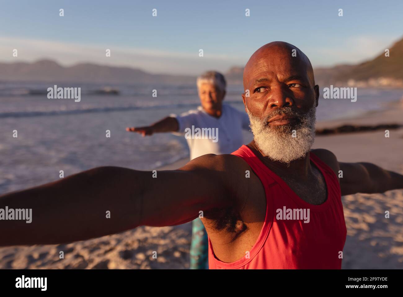 Senior african american couple performing stretching exercise together at the beach Stock Photo