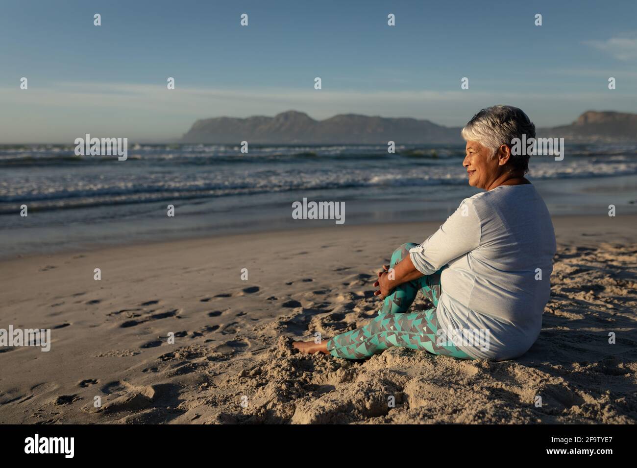 Senior african american woman smiling while sitting on the beach Stock ...