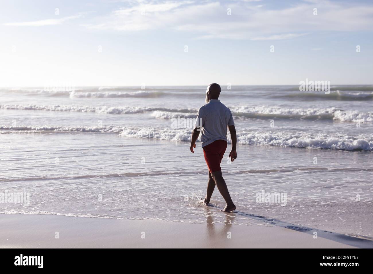 Rear view of senior african american man walking on the beach Stock ...