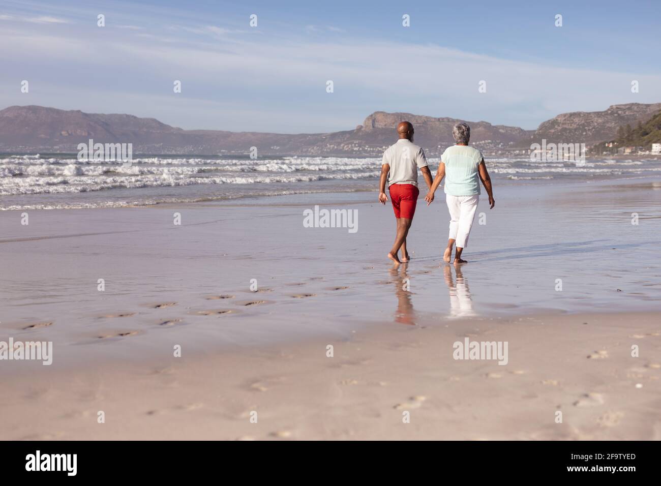Senior african american couple holding hands while walking on the beach ...