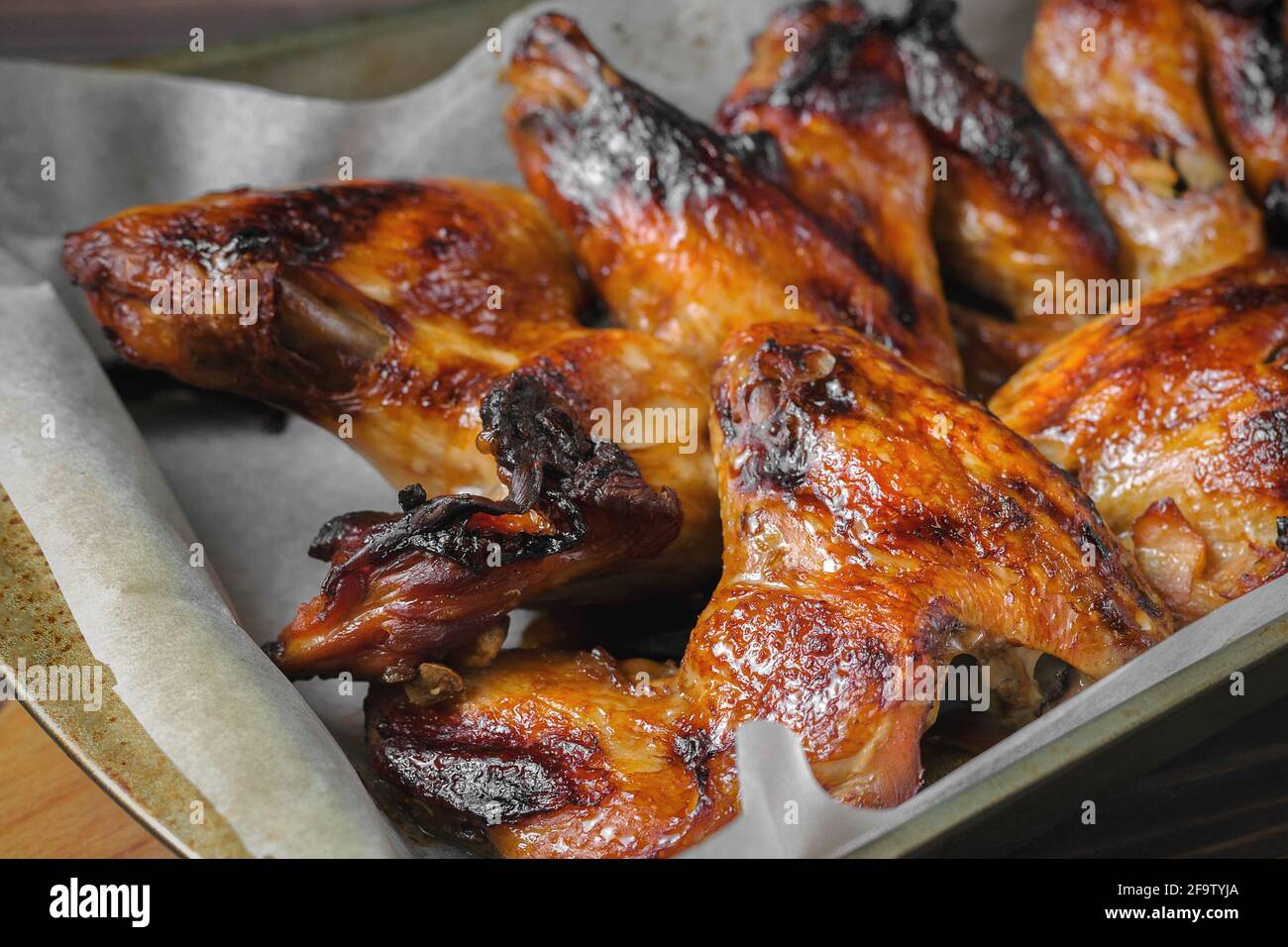 Baked chicken wings on a baking sheet, with a golden crispy crust. Stock Photo