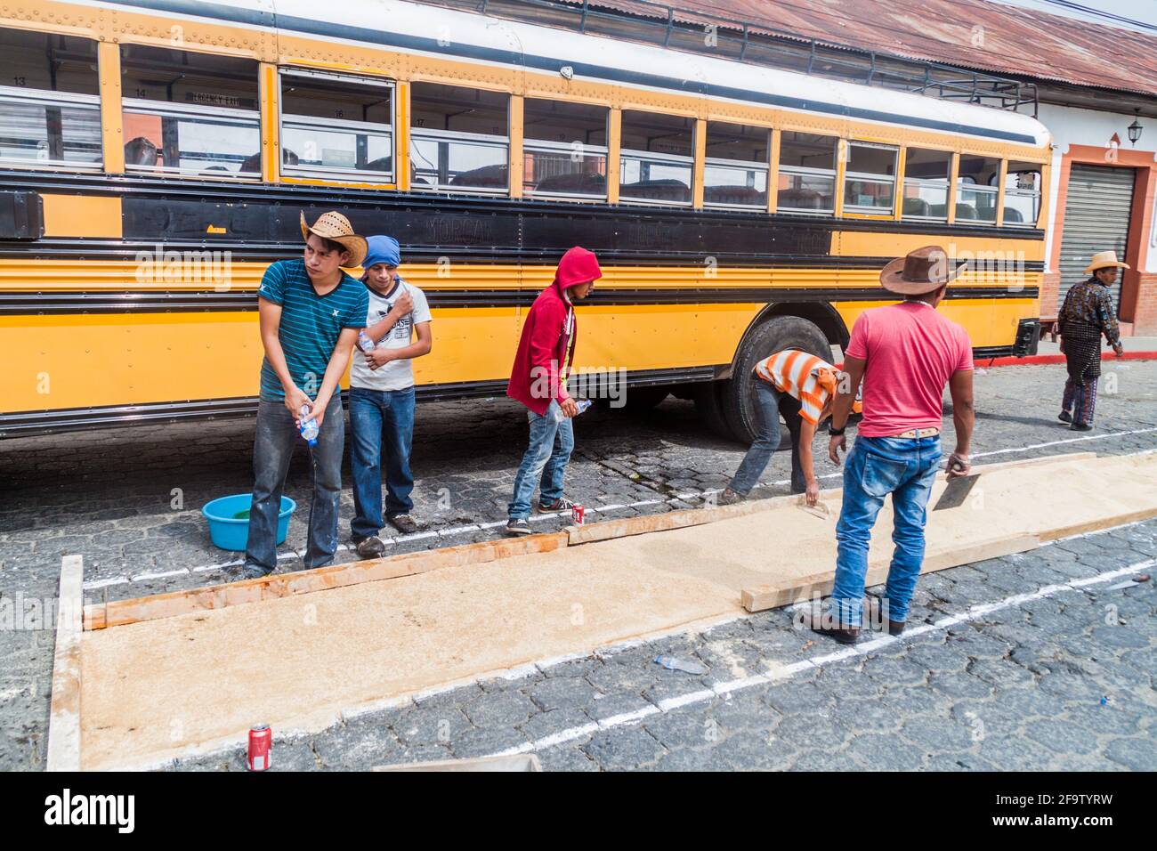 PANAJACHEL, GUATEMALA - MARCH 25, 2016: People decorate Easter carpets in front of a local bus in Panajachel village, Guatemala. Stock Photo