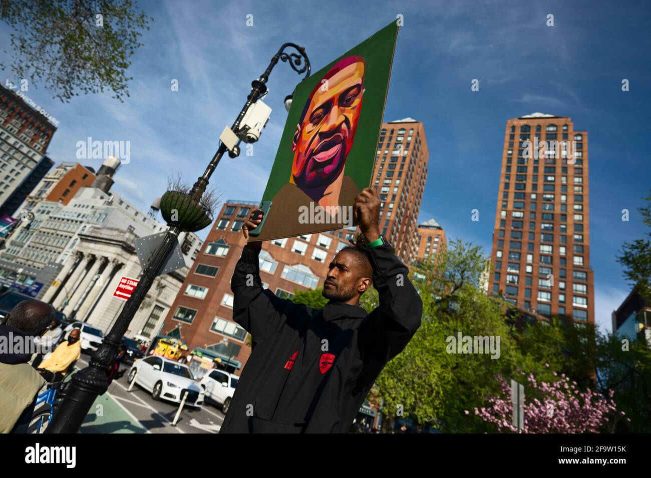 New York, New York, USA 20 April 2021.  Moments after former Minneapolis police officer Derek Chauvin was convicted of murdering George Floyd, defund police activist holds portrait of Floyd in front of crowd in New York's Union Square. Stock Photo
