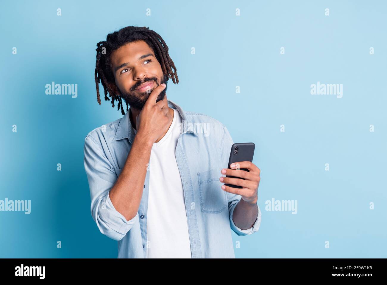 Portrait of attractive minded guy using gadget creating new post media comment isolated over bright blue color background Stock Photo