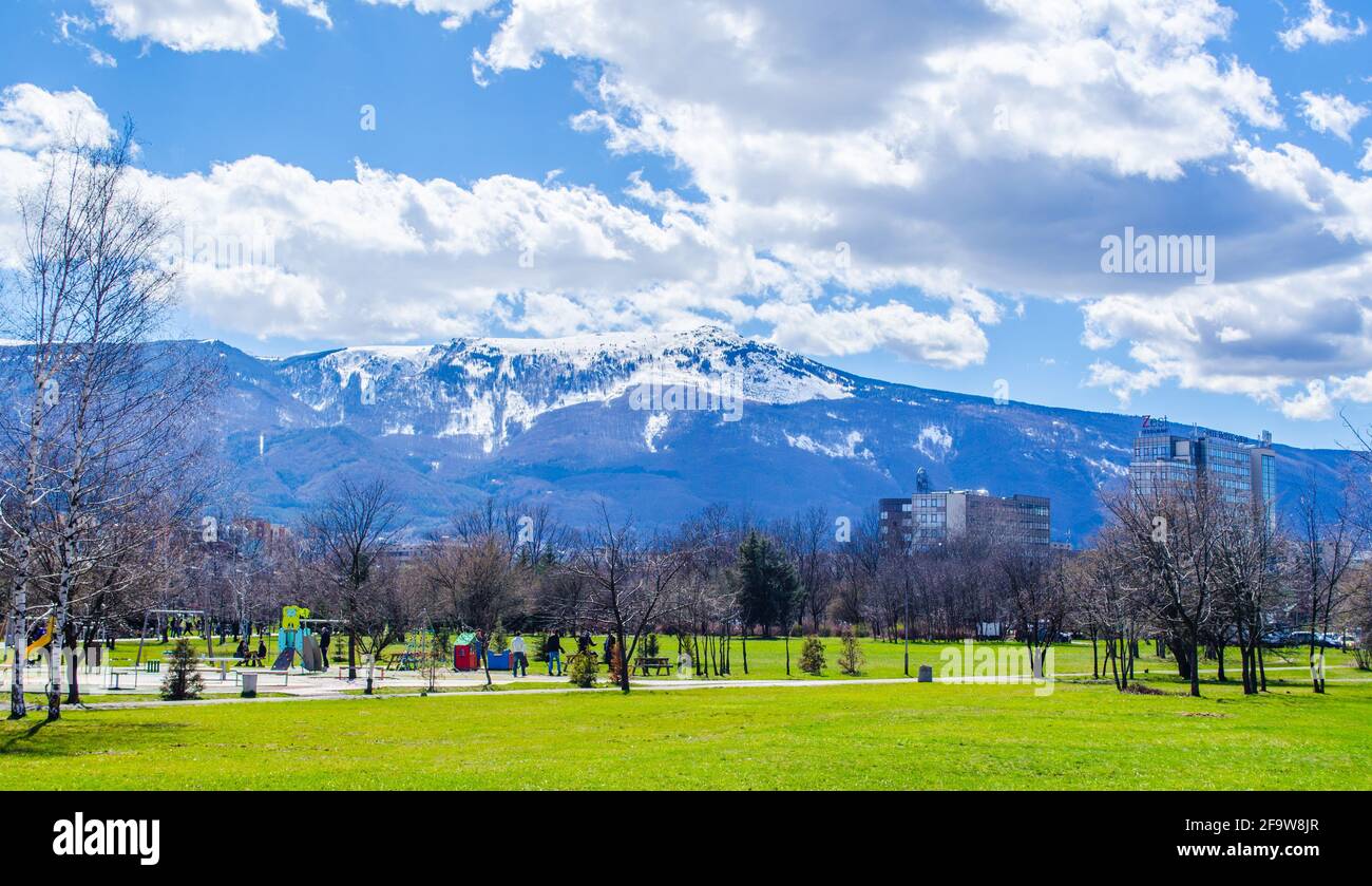 SOFIA, BULGARIA, MARCH 25, 2015: young bulgarians are walking through park in student city in sofia with vitosha mountain on background. Stock Photo