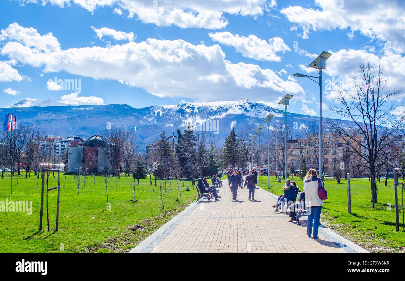 SOFIA, BULGARIA, MARCH 25, 2015: young bulgarians are walking through park in student city in sofia with vitosha mountain on background. Stock Photo