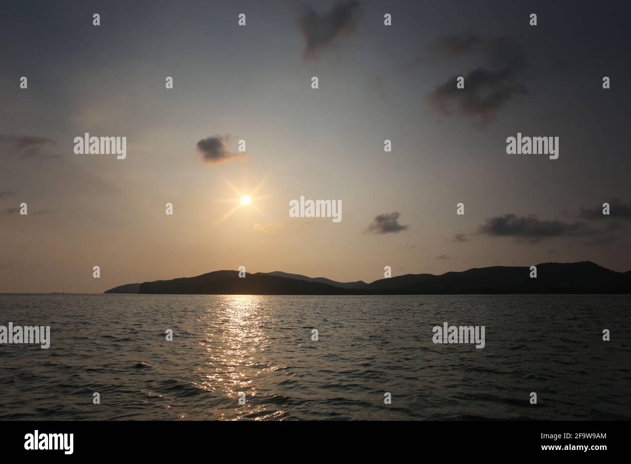 Sunset from the island in the sea,Landscape of sea and mountains in the evening with bright sky and near twilight time. Stock Photo