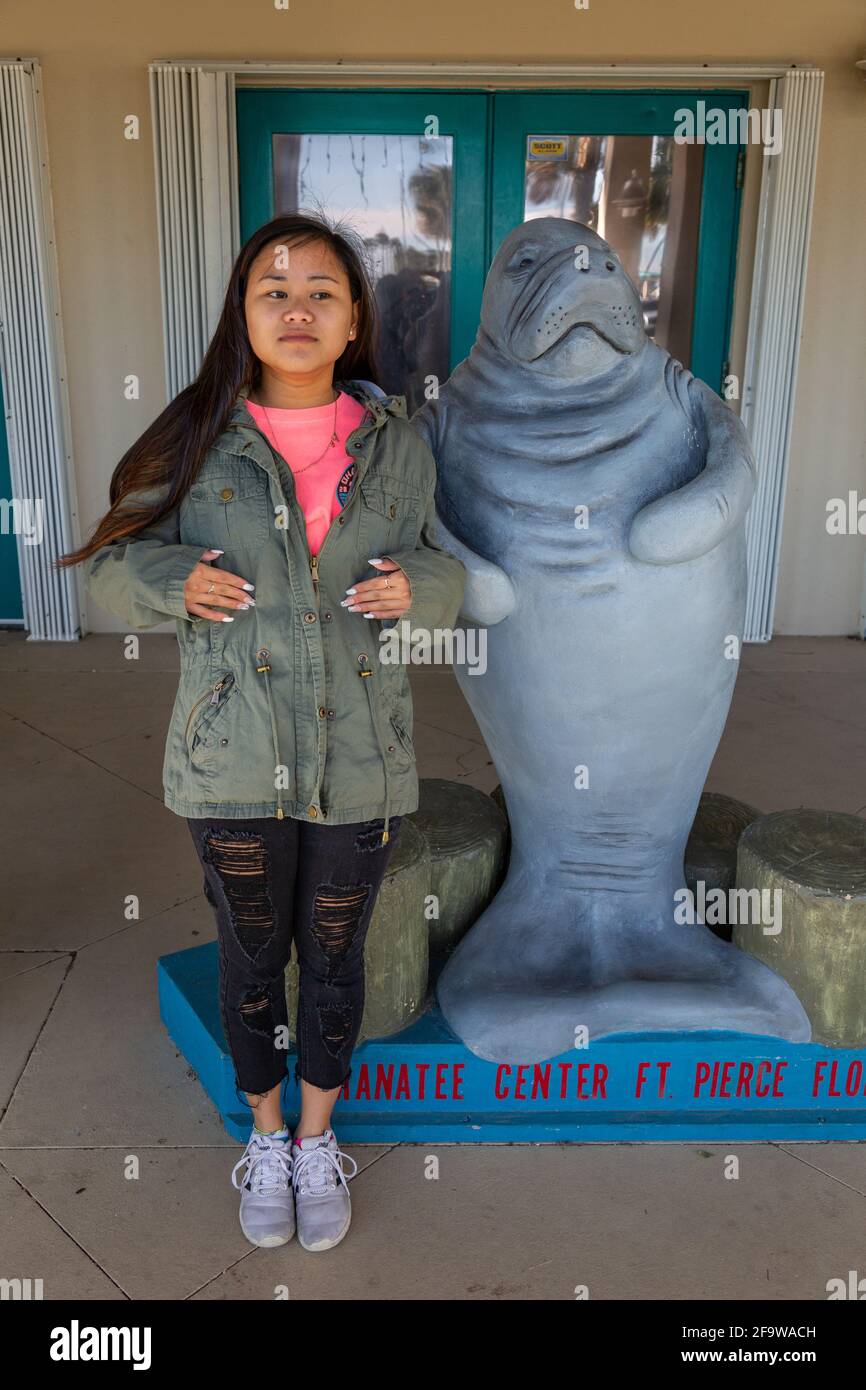 A teenage girl mimics the manatee statue at the Manatee Center in Fort