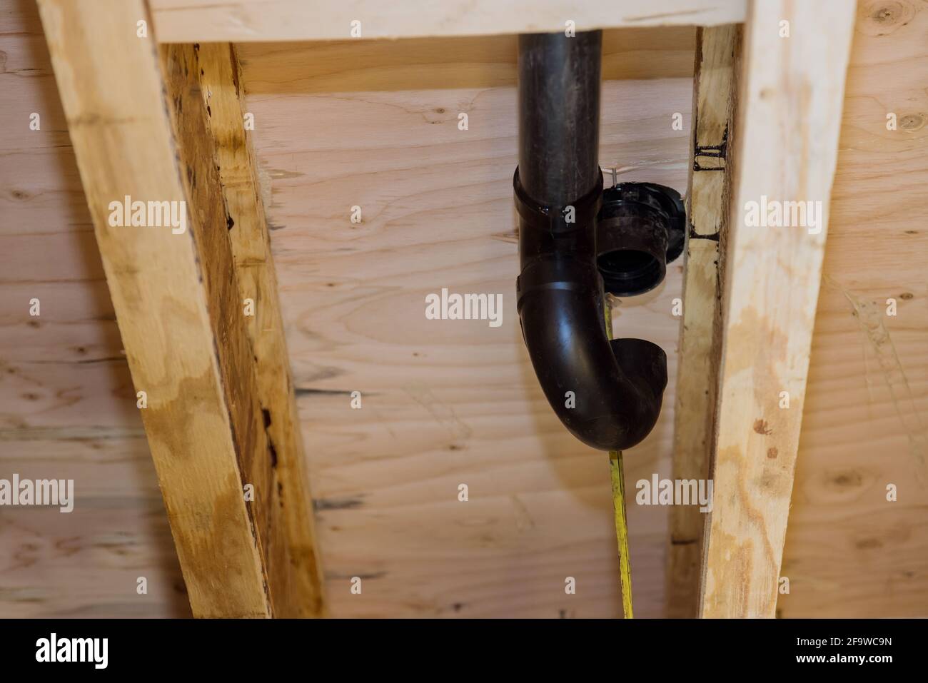 PVC plastic toilet sewer drain pipe in the plumber gluing, on wooden frame beam of house Stock Photo