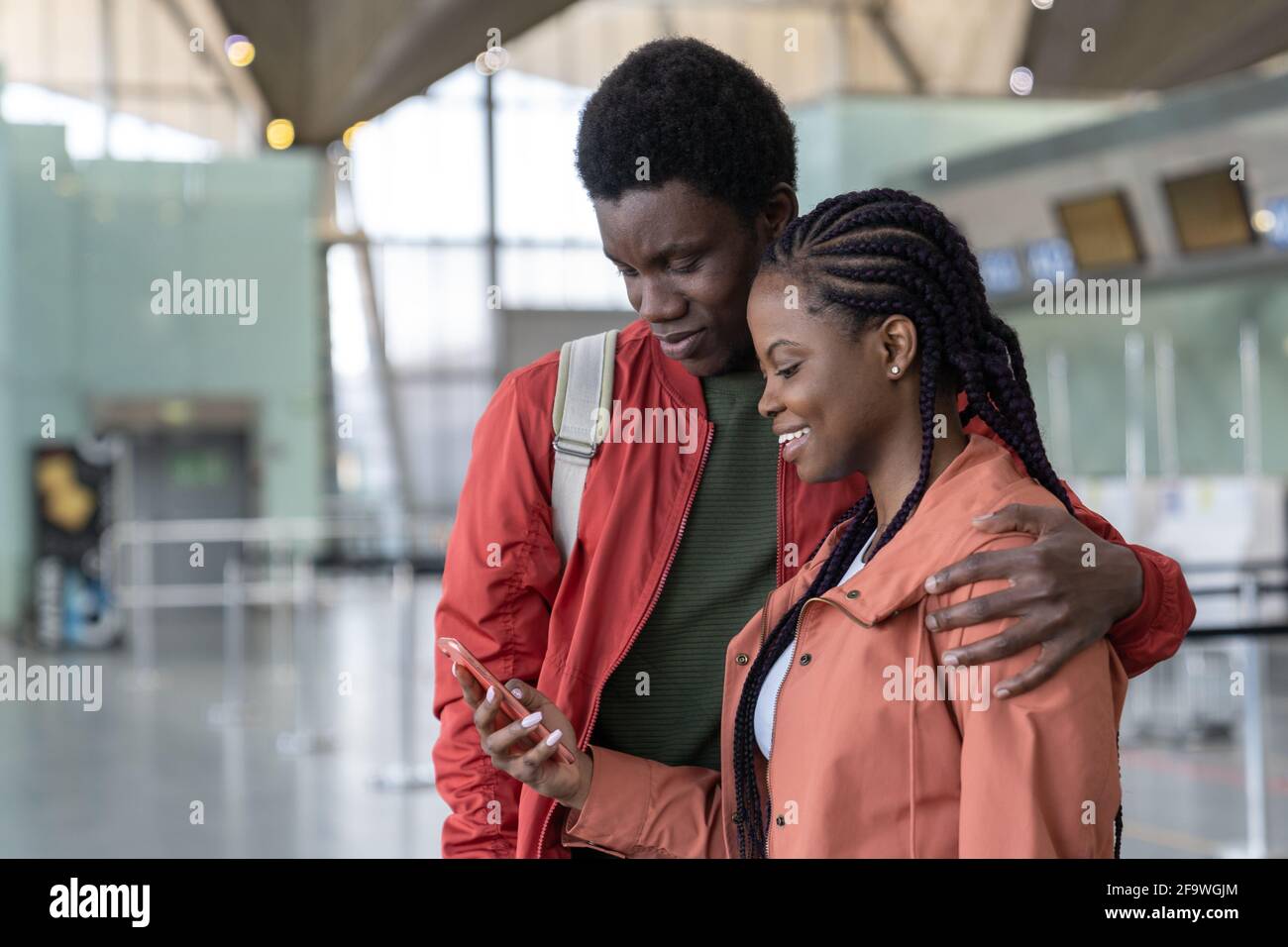 Loving black traveler couple wait for flight in airport terminal hug ...