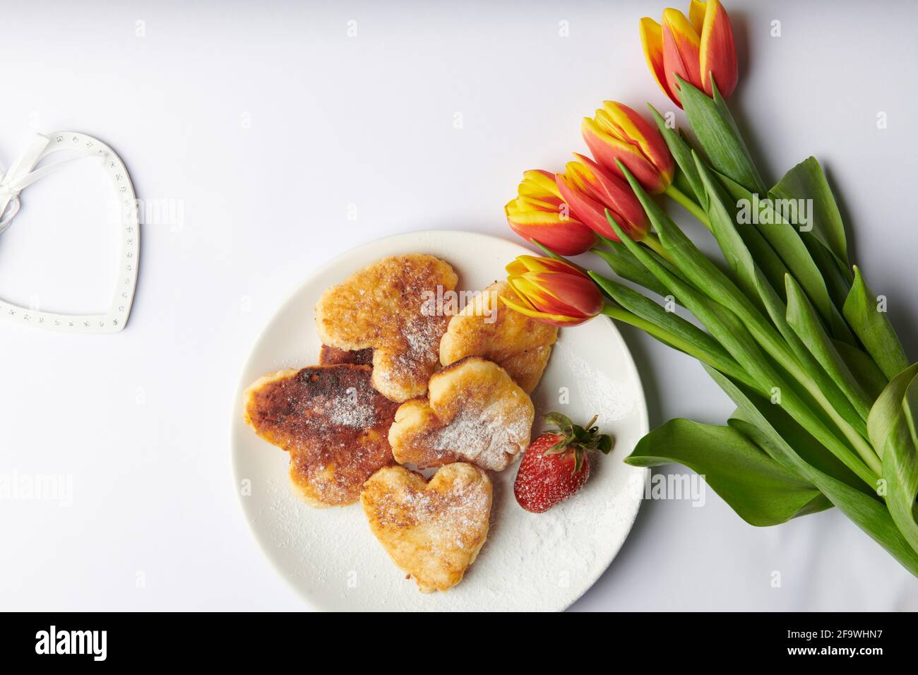 a bouquet of tulips with strawberries cheesecakes in the form of hearts  Stock Photo
