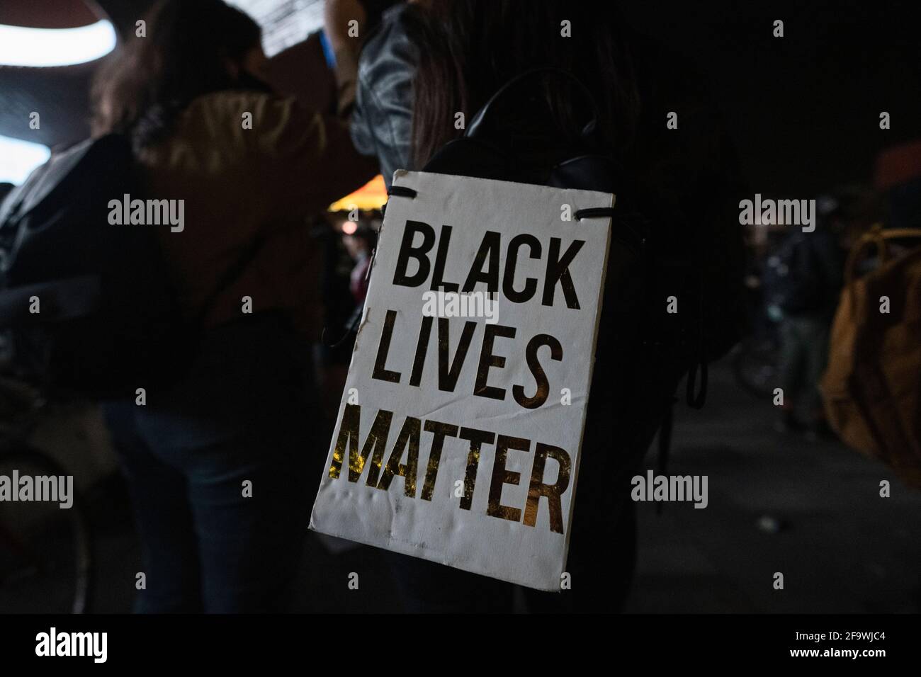 Brooklyn, New York, USA 20 Apr 2021. Black Lives Matter sign taped to woman's backpack as protesters gather at Barclays Center hours after a jury found former Minneapolis police officer Derek Chauvin guilty of murdering George Floyd in 2020. Stock Photo