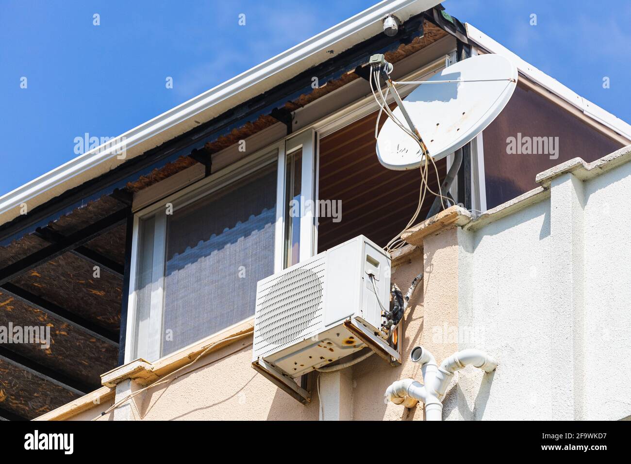 Satellite and air conditioning are mounted on the balcony of an old