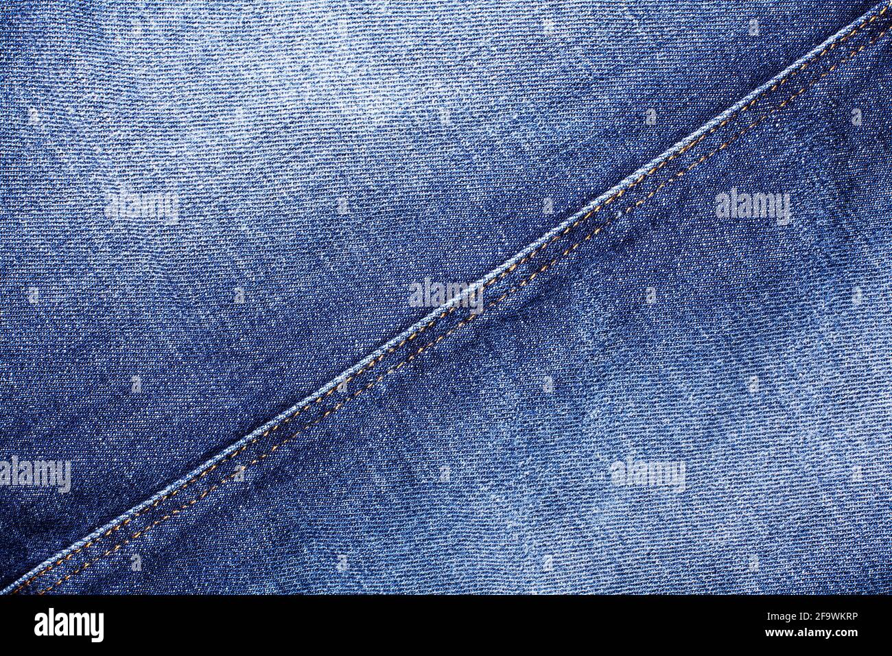 Blue jeans texture, diagonal seam closeup, thread stitch line, jean textile background, blue denim backdrop, faded jeans pattern, shabby indigo jeans Stock Photo