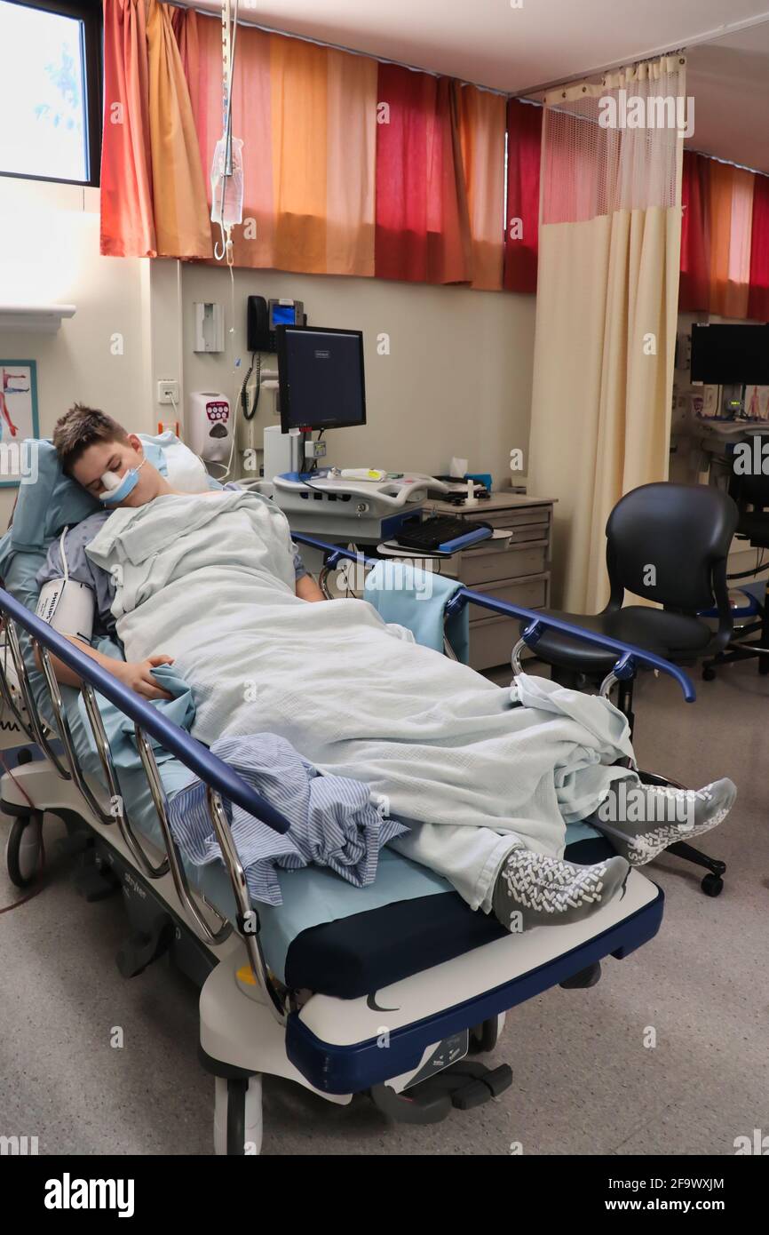 Teenage boy sleeping in a hospital bed with bandages on his face after