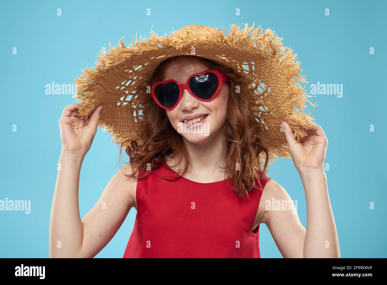 Girl in a beach Straw hat in sunglasses curly hair fun blue background ...