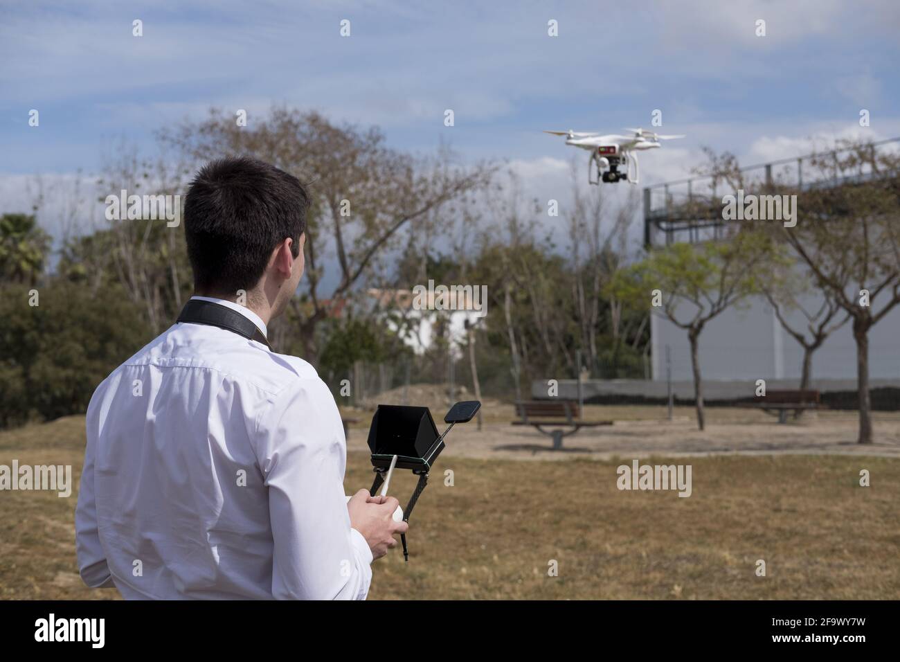 Young male in a flight school uniform piloting during a drone flight  practice in a field with trees Stock Photo - Alamy