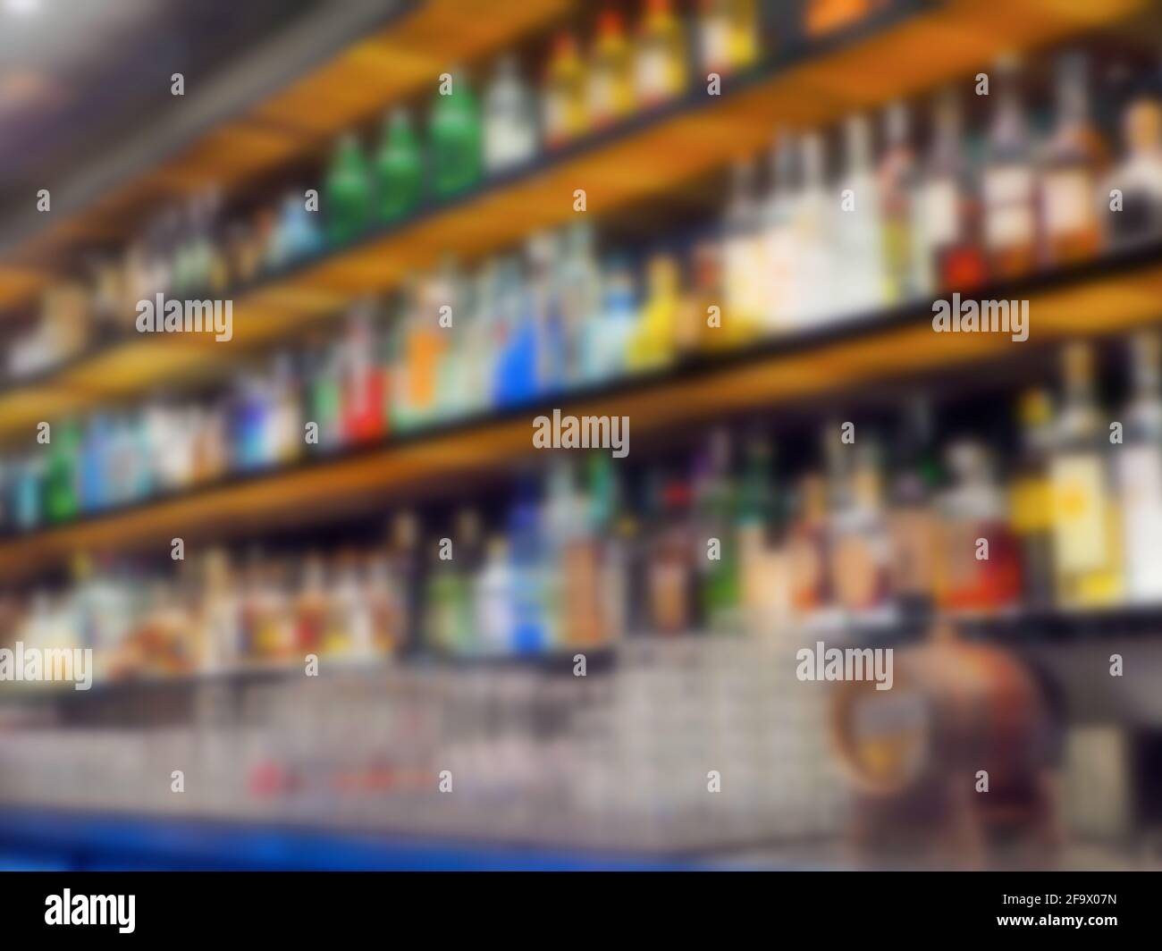 Blurred background of a bar with lit counters showing various drinks available Stock Photo