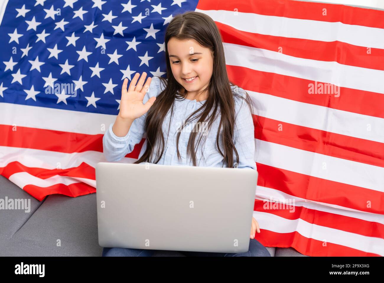 Back to online school education. Difficult to speak English. Kid doing homework on computer. Student studying on laptop over American flag. Tutor Stock Photo