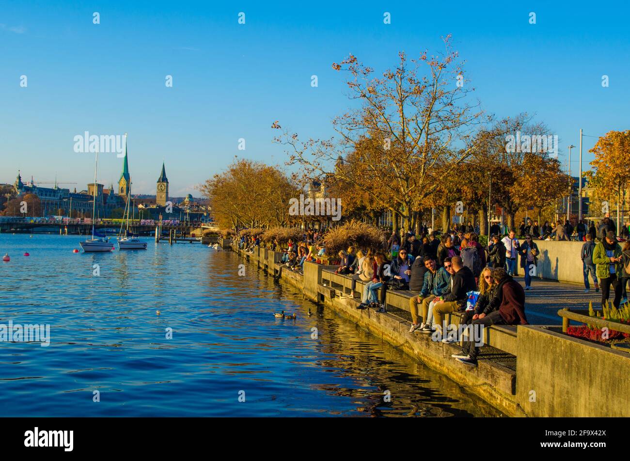 ZURICH, SWITZERLAND, OCTOBER 24, 2015: people are walking on a sunny promenade along the zurich lake in switzerland during late autumn afternoon Stock Photo