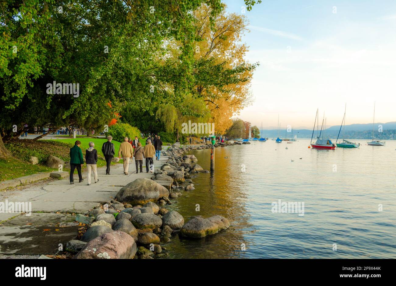 ZURICH, SWITZERLAND, OCTOBER 24, 2015: people are walking on a sunny promenade along the zurich lake in switzerland during late autumn afternoon Stock Photo