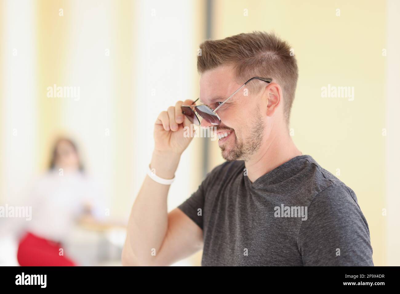 Young man with stylish hairstyle putting on sunglasses Stock Photo - Alamy