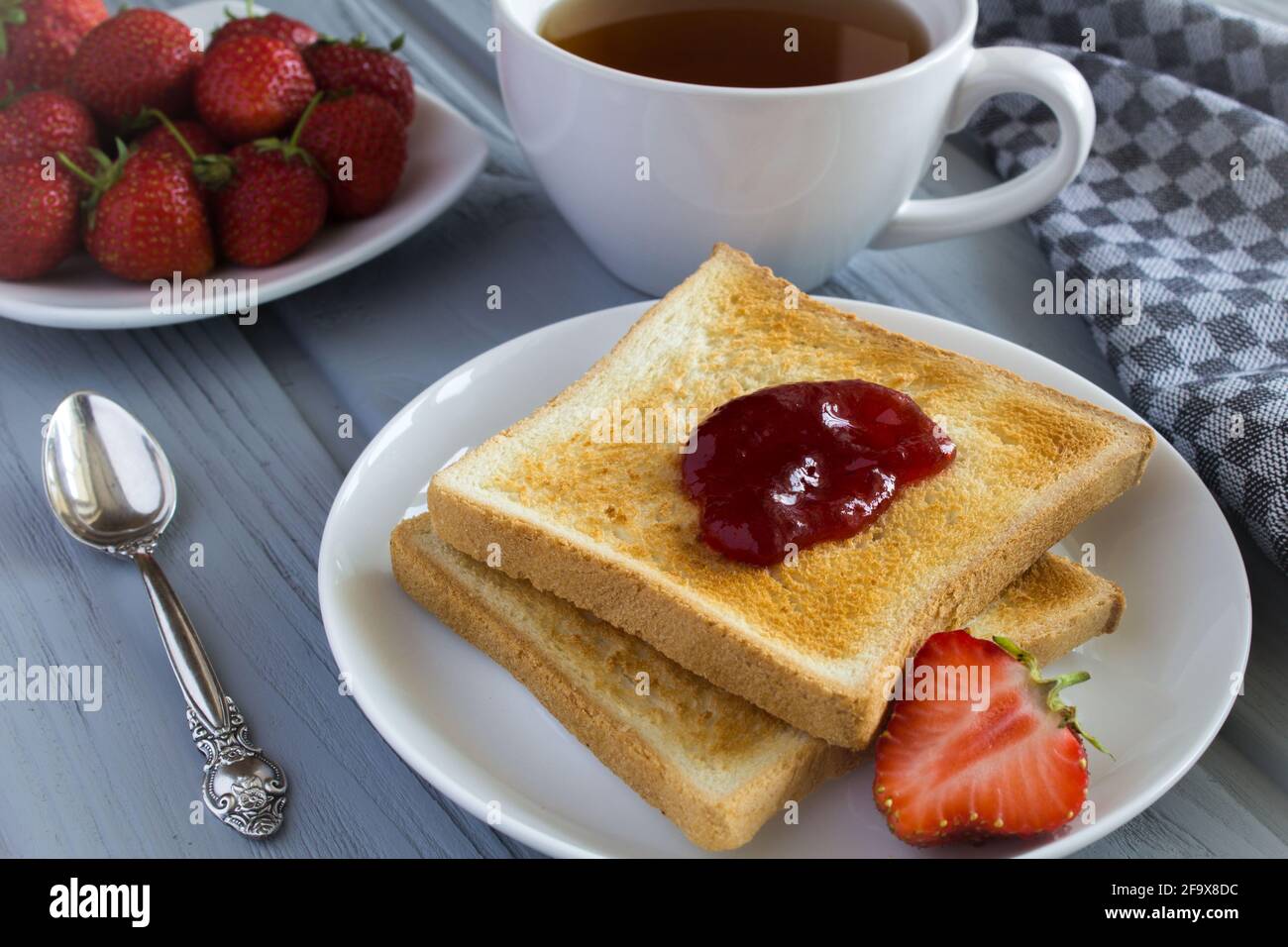 Bread toast with strawberry jam and tea on the grey background Stock Photo