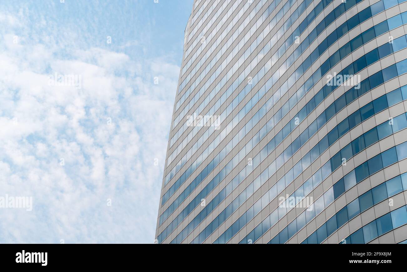 Beautiful modern high-rise glass building with reflection sky image, perspective view, blank space on blue sky and cloudscape, daylight image. Stock Photo