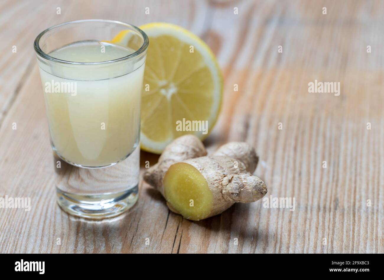 Ginger shot with lemon on wooden background. Stock Photo