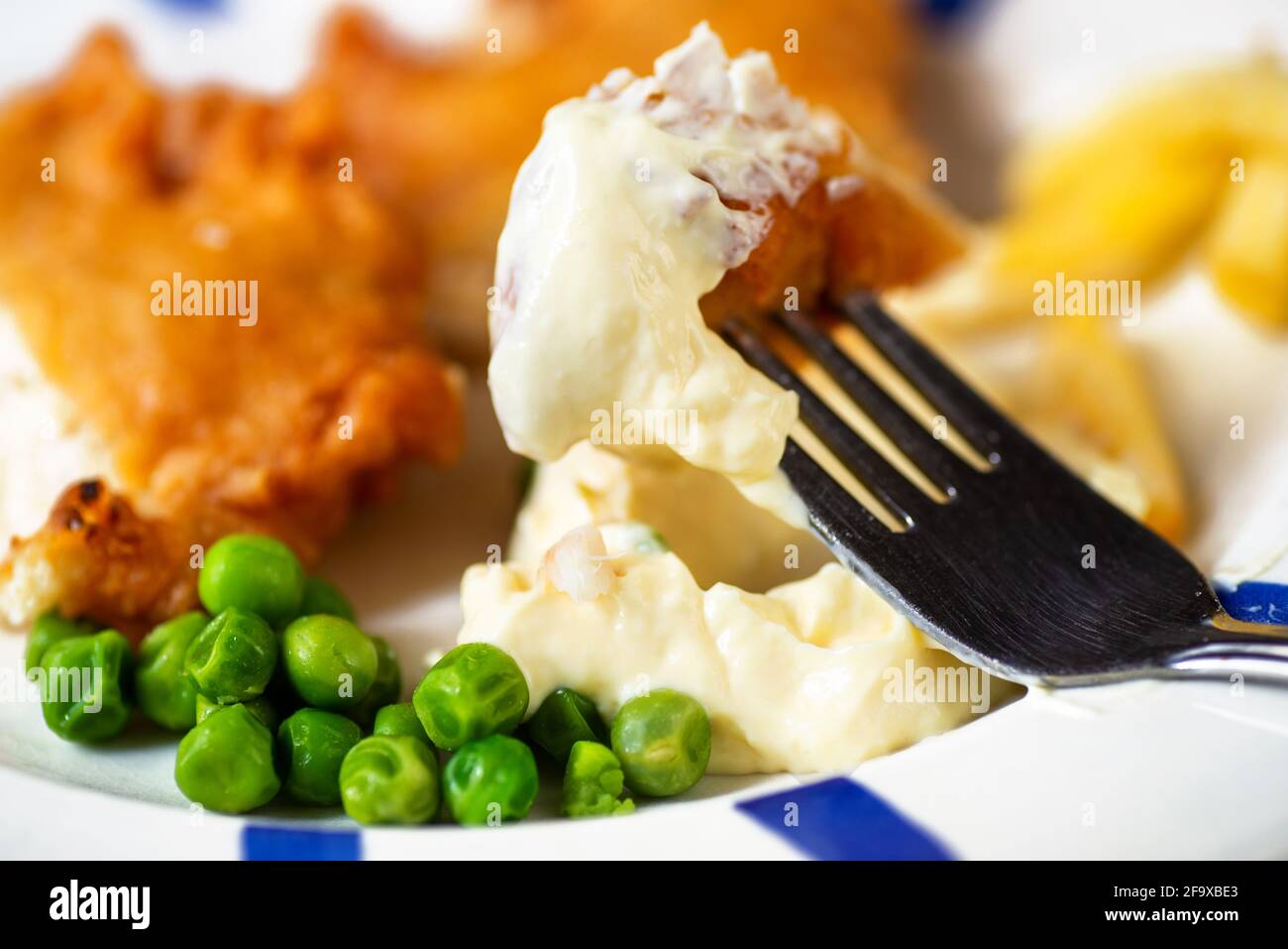 Plate with traditional street food meal, breaded fried fish and chips with pea and mayonnaise