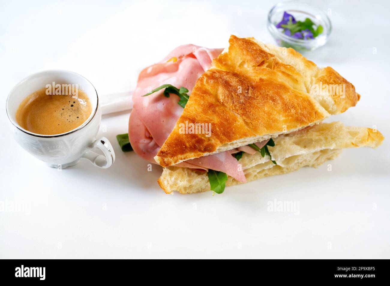 https://c8.alamy.com/comp/2F9XBF5/focaccia-pastry-sandwich-with-salami-and-rucola-cup-of-coffee-espresso-small-glass-cup-with-flower-white-background-festive-breakfast-or-snack-2F9XBF5.jpg