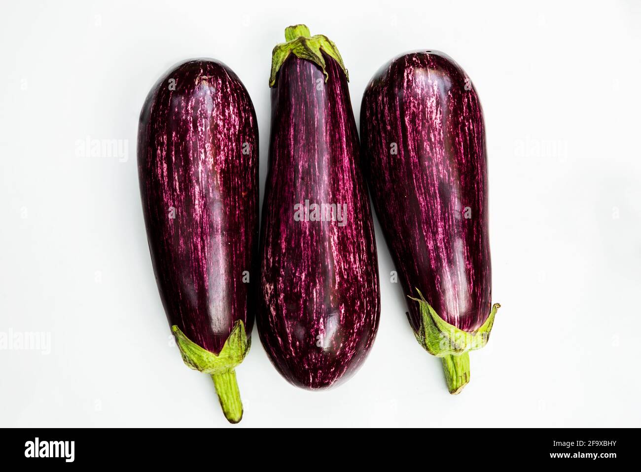 Three purple fruit of eggplant (aubergine) with white stripes, isolated