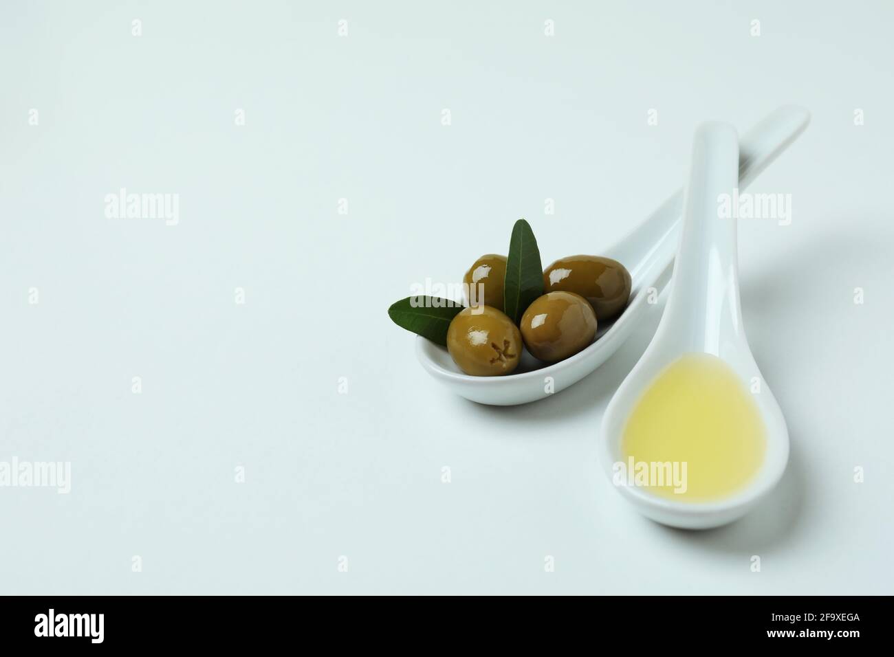 Spoons with olives and oil on white background Stock Photo - Alamy