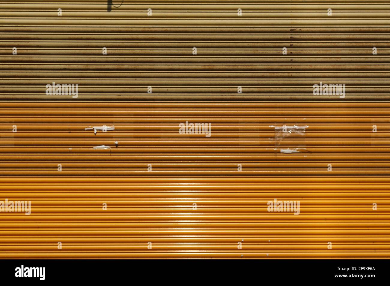 Shades of amber, orange, yellow, and mustard on a roller shutter in Preston, Lancashire, UK. Stock Photo
