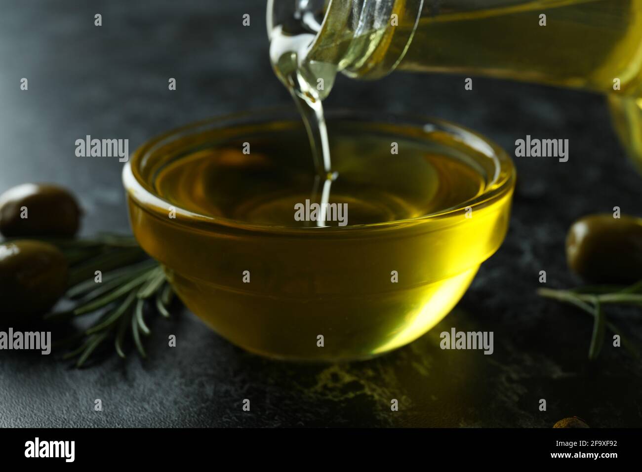 Olive oil pouring from bottle to bowl, close up Stock Photo