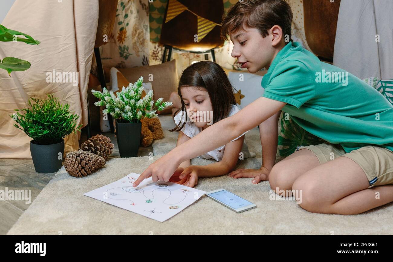 Children playing treasure hunting game in a diy tent at home Stock Photo