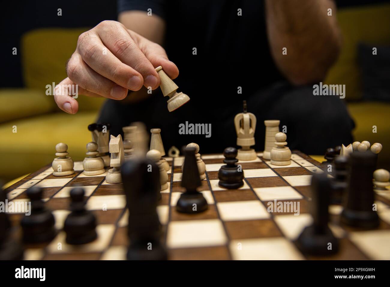 Hand taking next step on chess game. Human hand moving wooden dark bishop piece Stock Photo