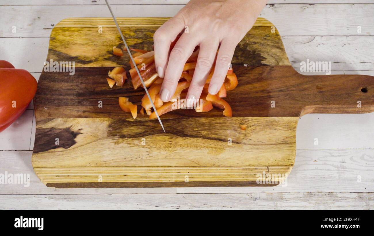 Mincing organic red bell peppers on a wood cutting board Stock Photo ...