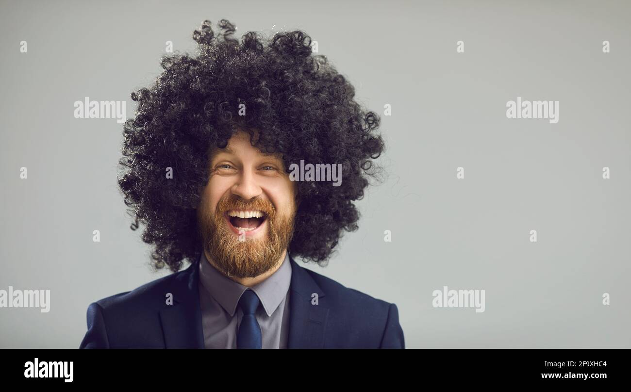 Gray copy space banner with portrait of funny laughing man in suit and crazy curly wig Stock Photo