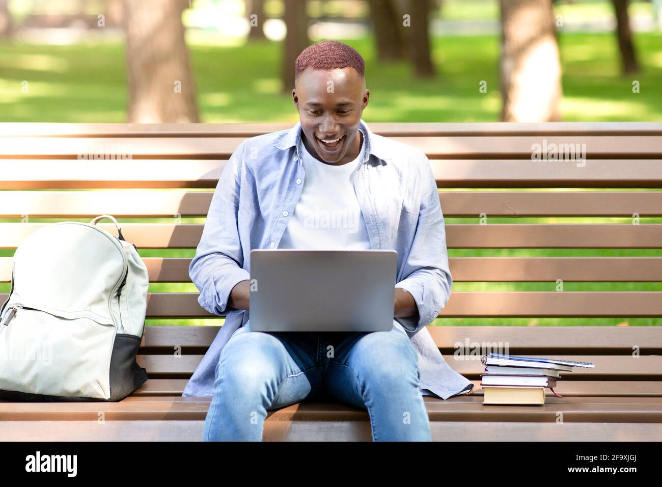 Excited black student looking at laptop screen, cannot believe his success at park Stock Photo