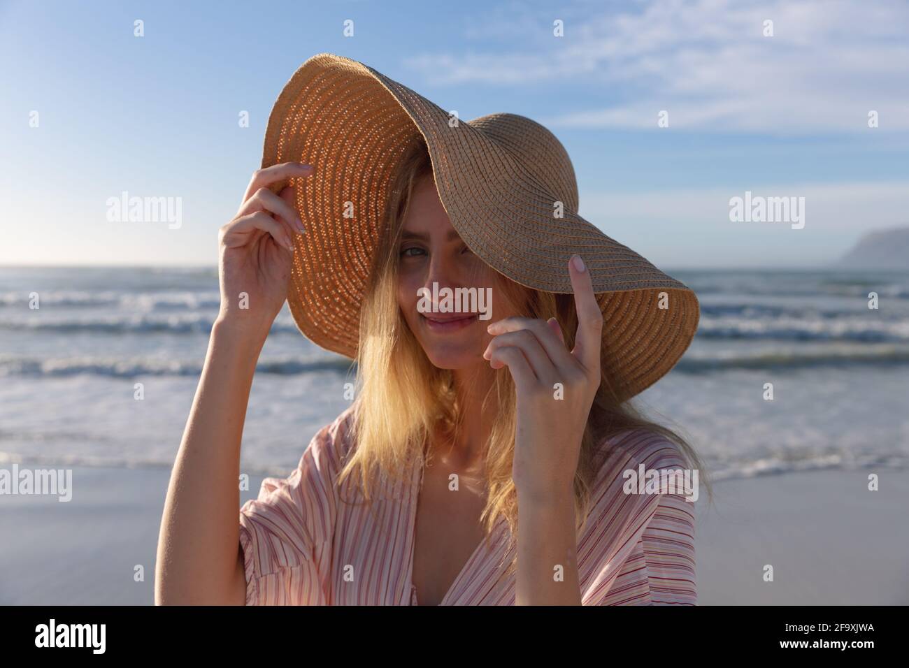 Caucasian woman wearing hat looking at camera and smiling at the beach Stock Photo