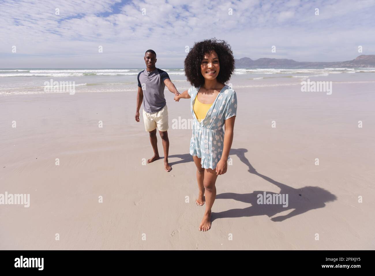 African american couple walking and holding hands at the beach smiling ...