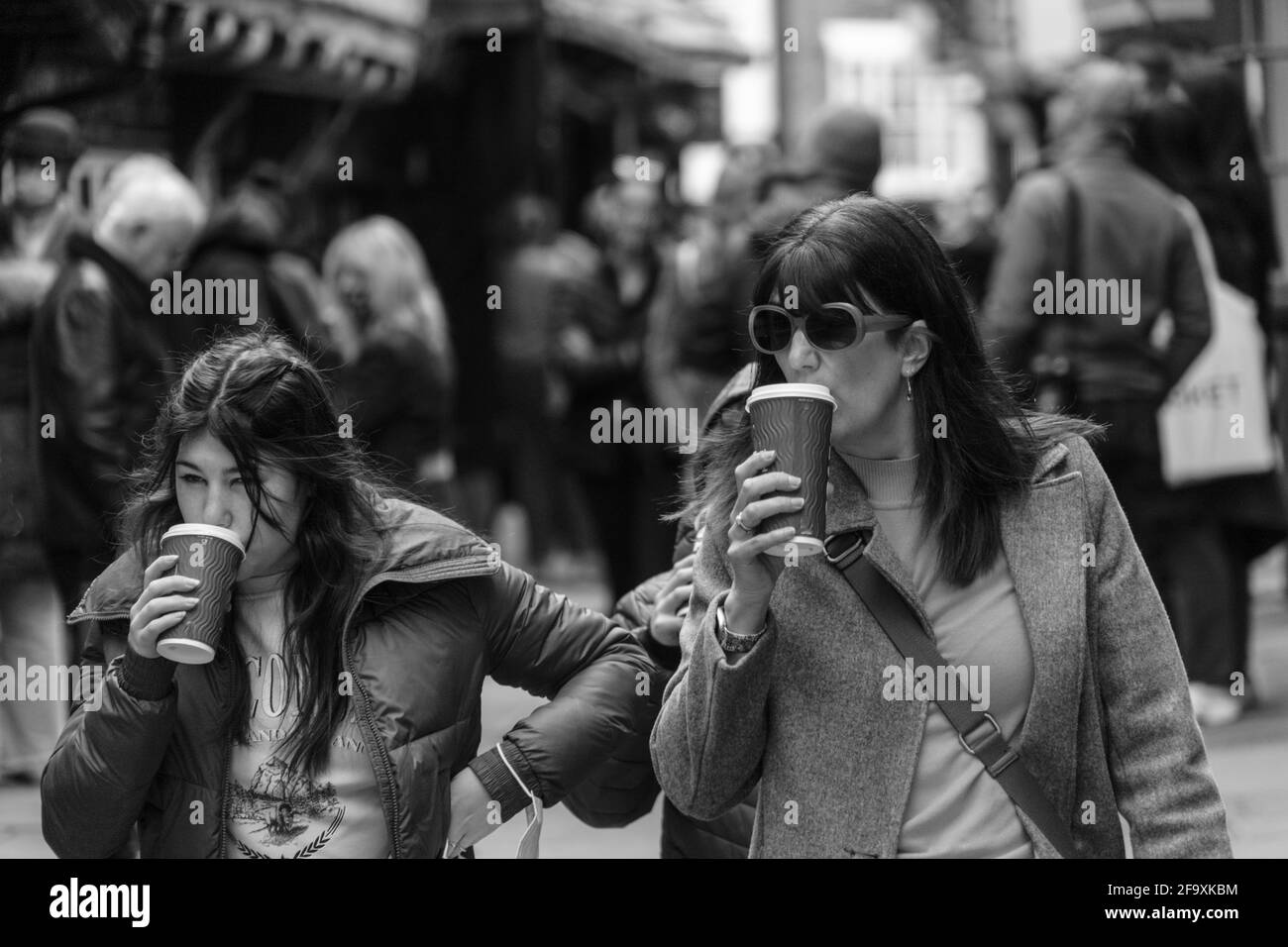Two ladies strolling down the street in York, England, drinking coffee from disposable cups, North Yorkshire, England, UK. Stock Photo