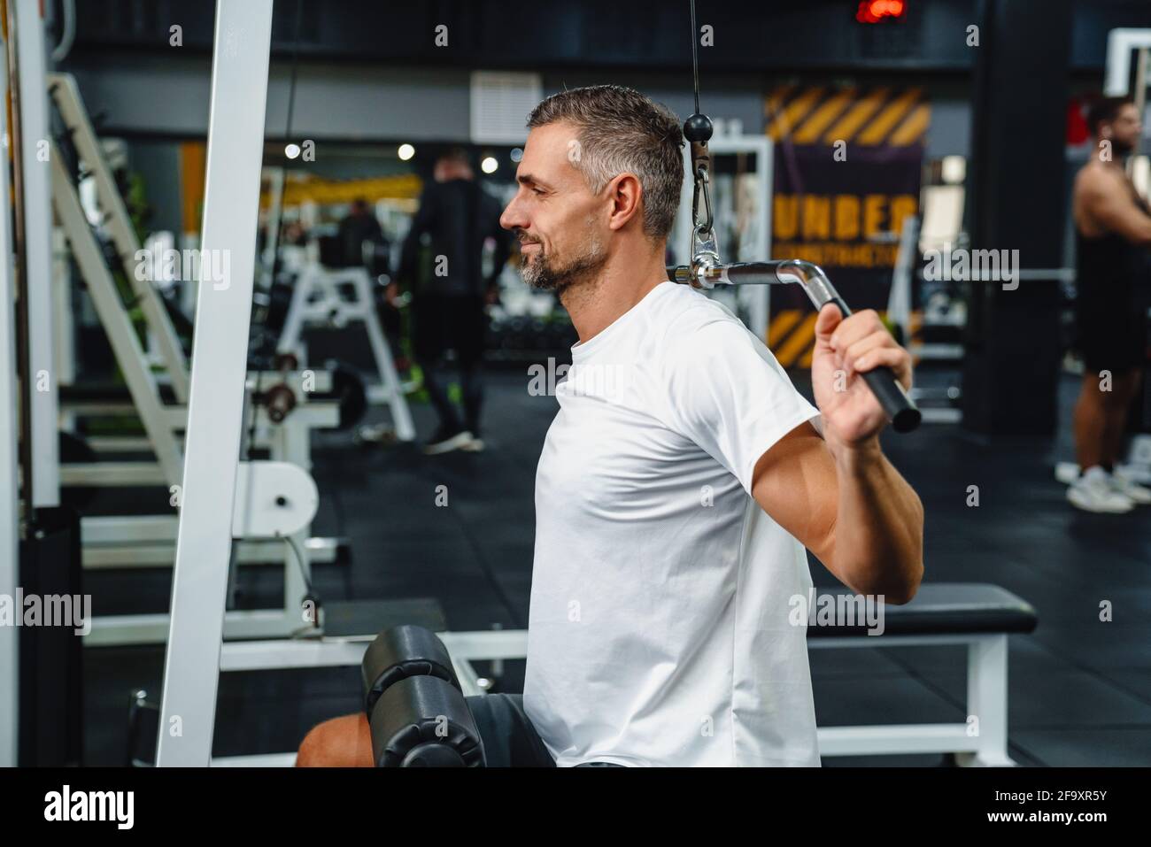 Attractive confident healthy sports man using seated lat pulldown