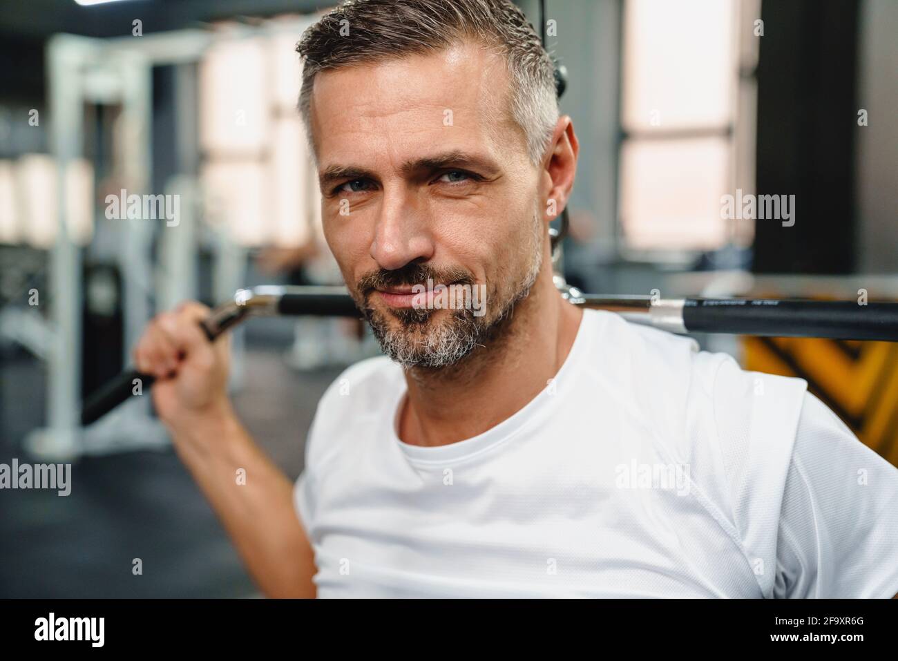 Attractive confident healthy sports man using seated lat pulldown
