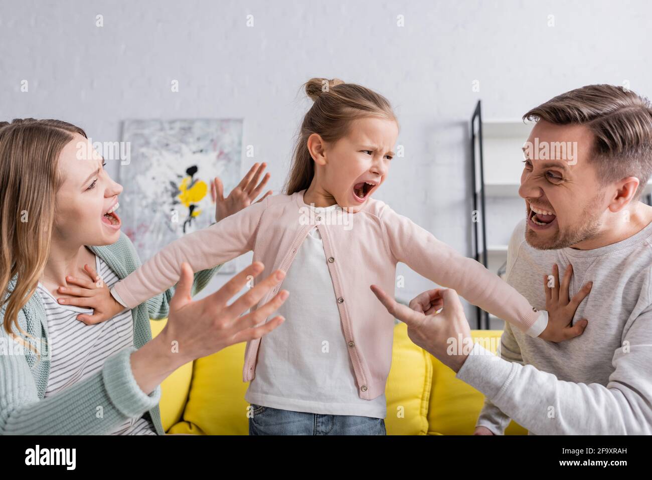 Yelling child pushing away quarreling parents Stock Photo